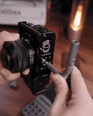 Owner handheld clip tightening a mirrorless camera cage hex screw on a wooden desk