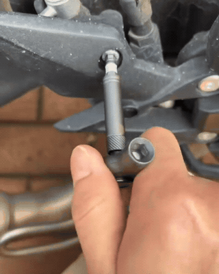 Owner handheld clip tightening a scooter brake caliper and fairing bolt outdoors